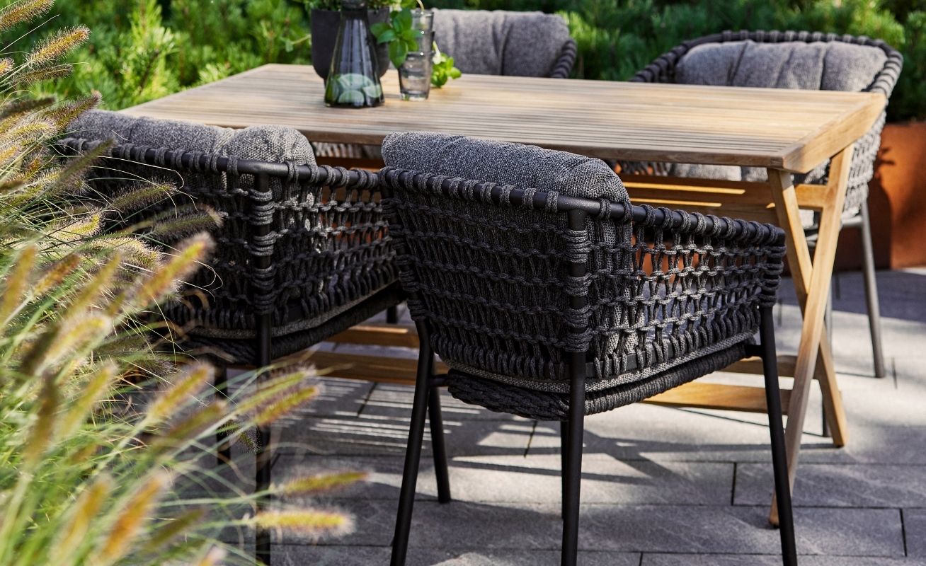 Ocean Outdoor Dining Chair in Dark Grey with the Natté Grey Optional Cushion Set at a table - Danish Design Co Singapore