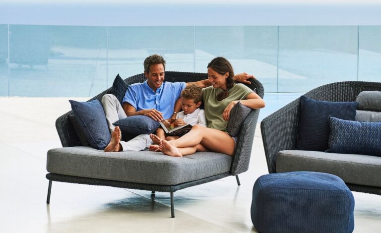Cane-line Mega Outdoor Daybed in Dark Grey with Light Grey Cushions with family in it - Danish Design Co Singapore