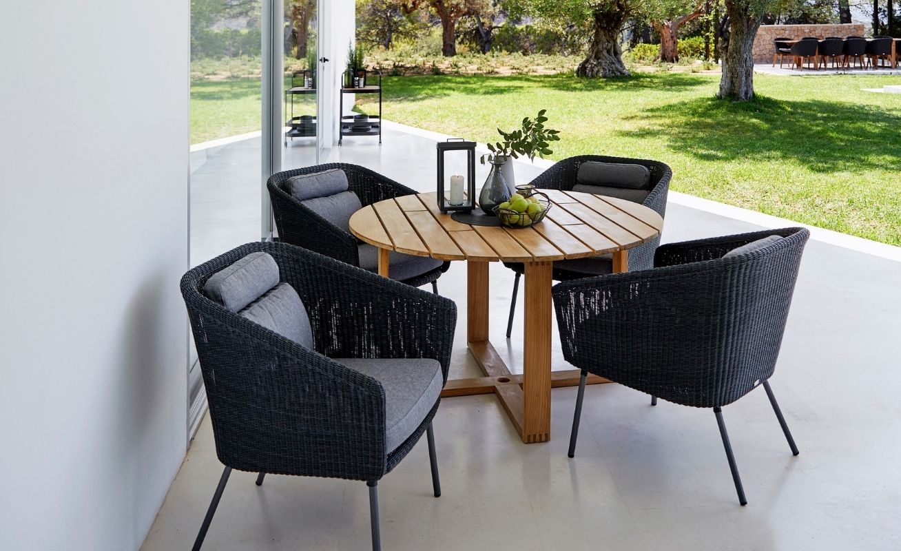 Cane-line Mega Outdoor Dining Chair in Dark Grey with Light Grey Cushions around a teak table - Danish Design Co Singapore